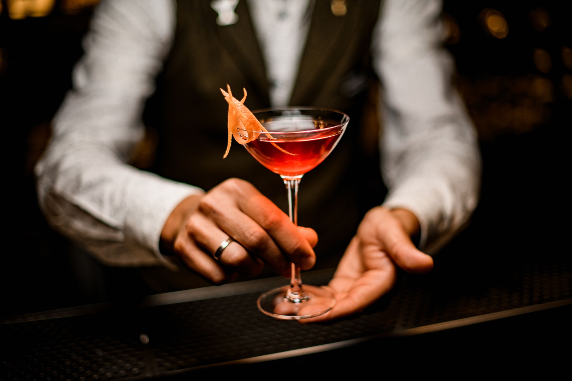 wine glass with trendy bright alcoholic cocktail in hands of male bartender
