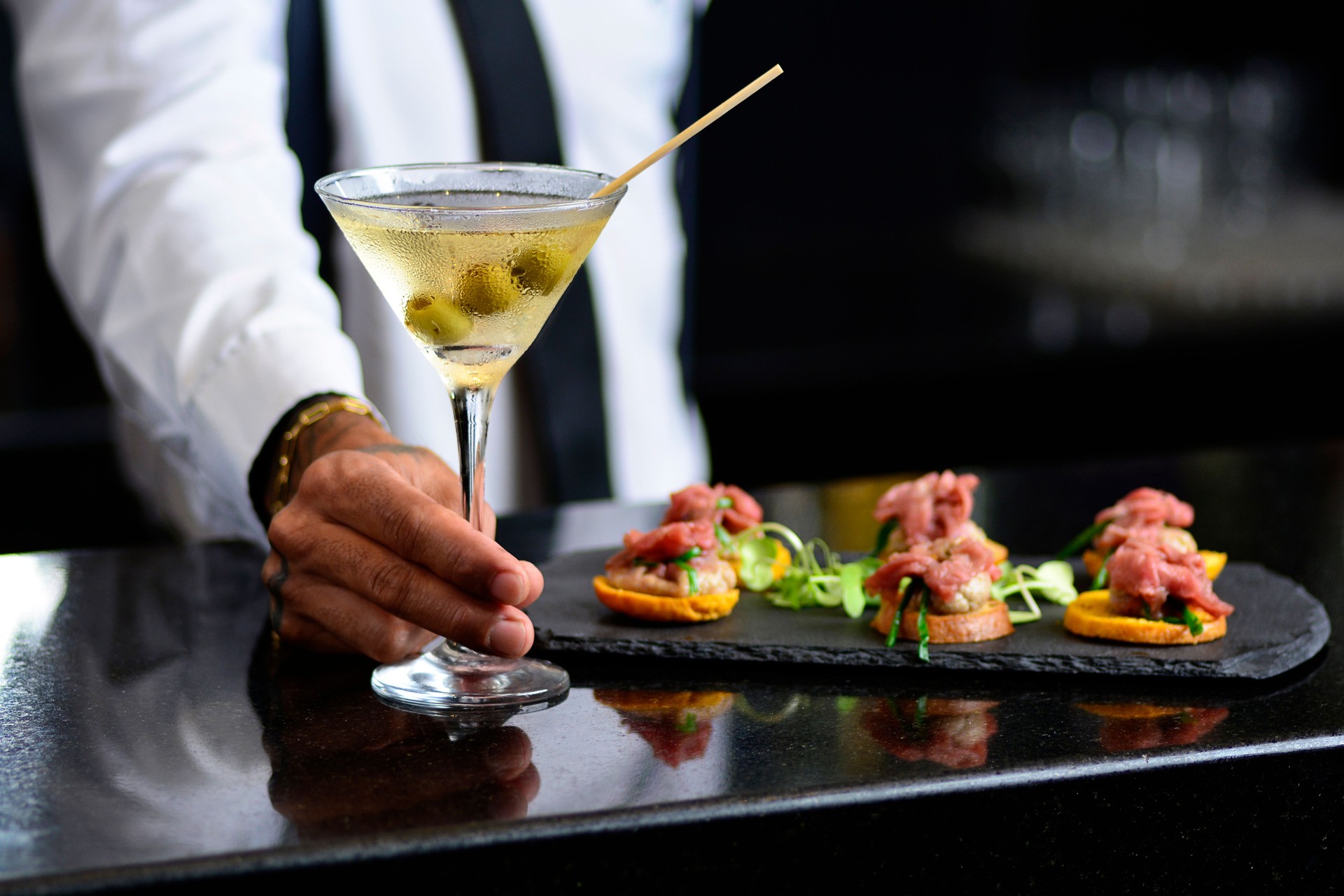 Waiter serving a drink and snacks a luxury bar